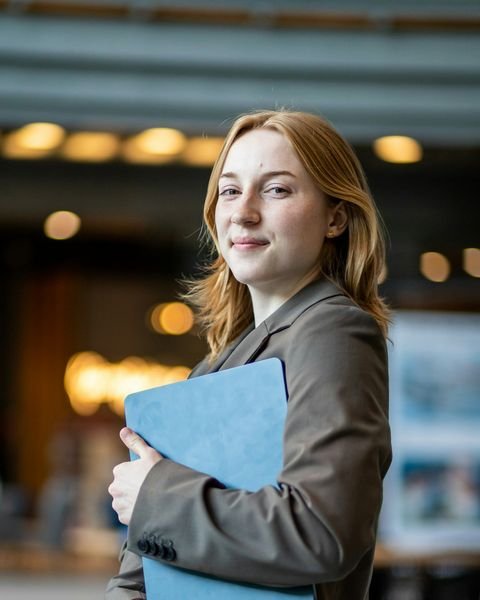 Portrait of Jordan M. Carter, smiling, holding a document folder