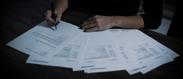 A signer reviewing and signing a set of documents with a pen